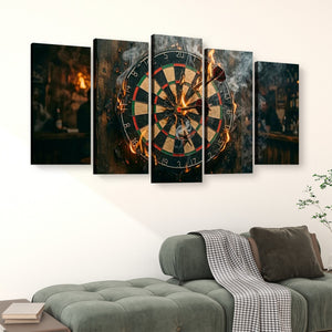 A 5-panel canvas wall art set depicting a dramatic dartboard scene with fire and smoke, displayed above a green sofa in a modern living room setting.