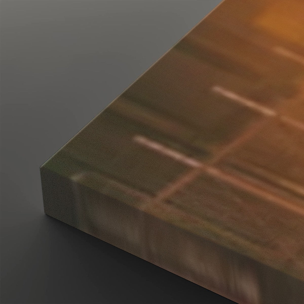 A close-up of a rectangular panel or board shown at an angle, with a warm coppery-brown reflective surface and a darker gray side edge, photographed on a dark gray background.