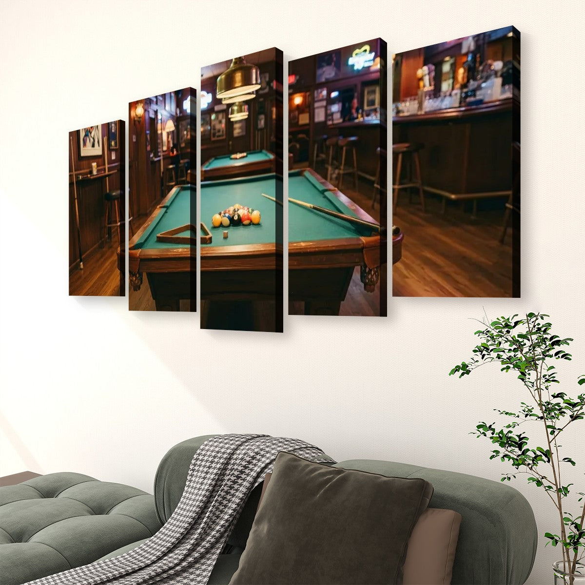 A five-panel canvas wall art set depicting a pool table in a dimly lit bar, displayed on a white wall above a green sofa with a throw blanket and a potted plant.