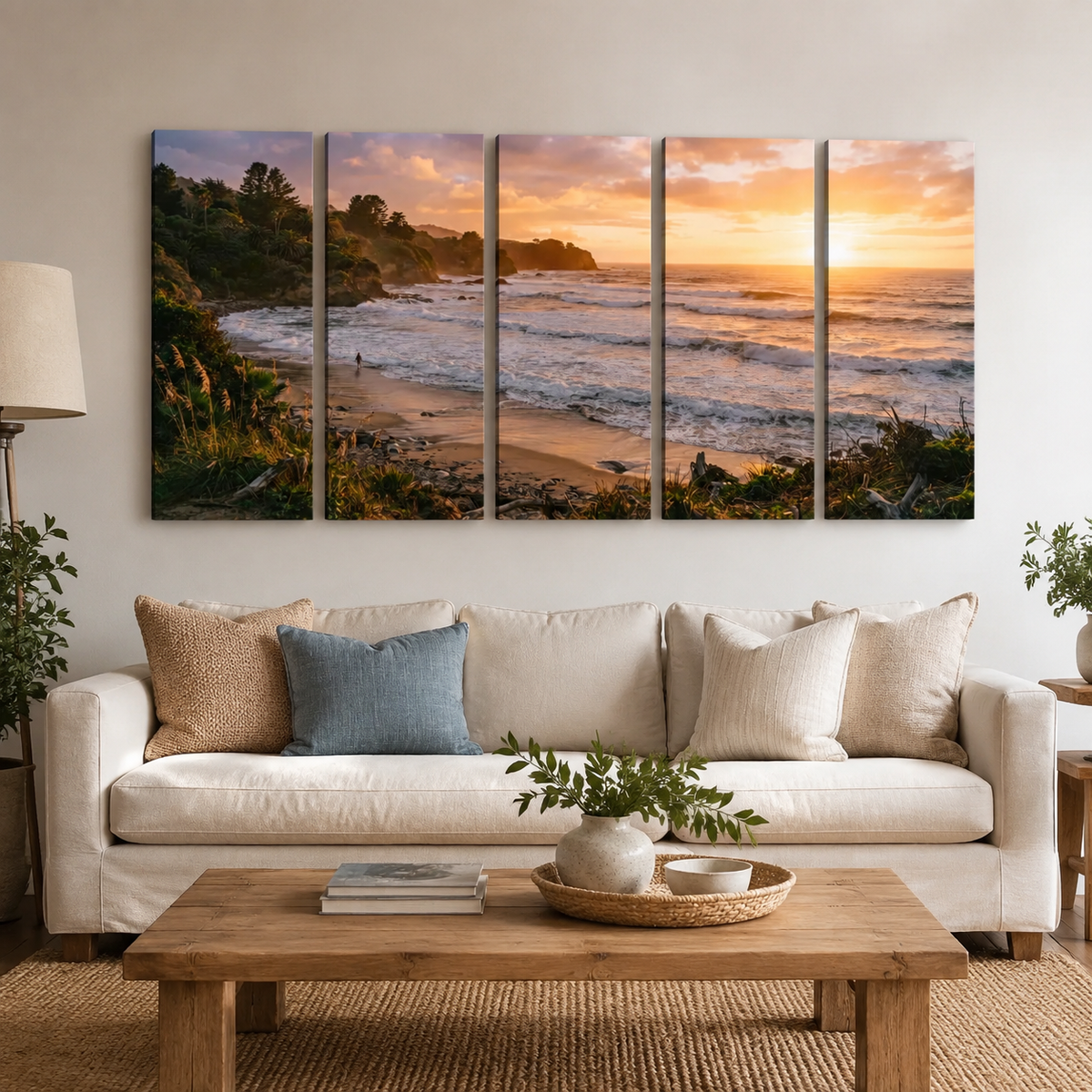 A five-panel canvas wall art set depicting a coastal beach sunset, displayed above a cream sofa in a modern living room setting.