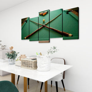 A 4-panel canvas wall art set depicting a green pool table with crossed pool cues and a billiard ball, displayed on a white wall above a dining table in a modern room setting.