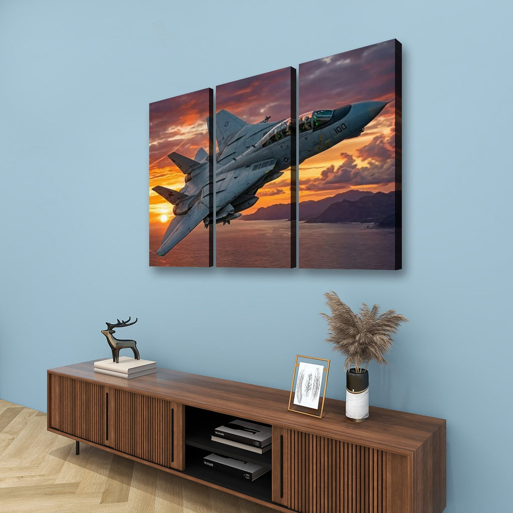 A three-panel canvas wall art set depicting a gray Grumman F-14 Tomcat military fighter jet flying over a sunset landscape, displayed on a light blue wall above a wooden console table with decorative items.