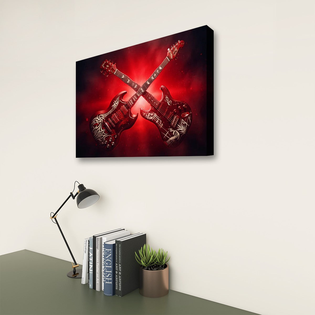 A rectangular wall art print showing two crossed electric guitars against a red and black background, displayed on a light wall above a desk with books, a lamp, and a small plant.