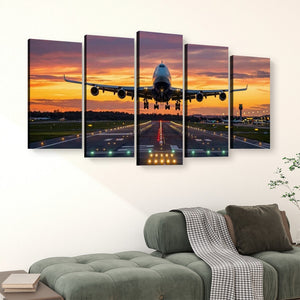 A five-panel canvas wall art set depicting a commercial airplane landing on a runway at sunset, displayed above a green sofa in a living room setting.