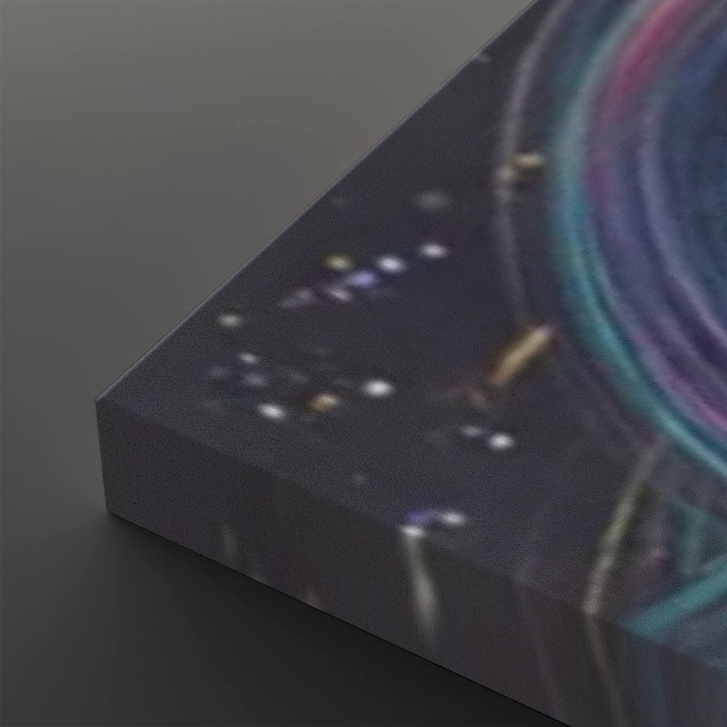 A close-up of a rectangular canvas or print showing a dark abstract cosmic scene with glowing white and multicolored light streaks, photographed on a dark gray background.