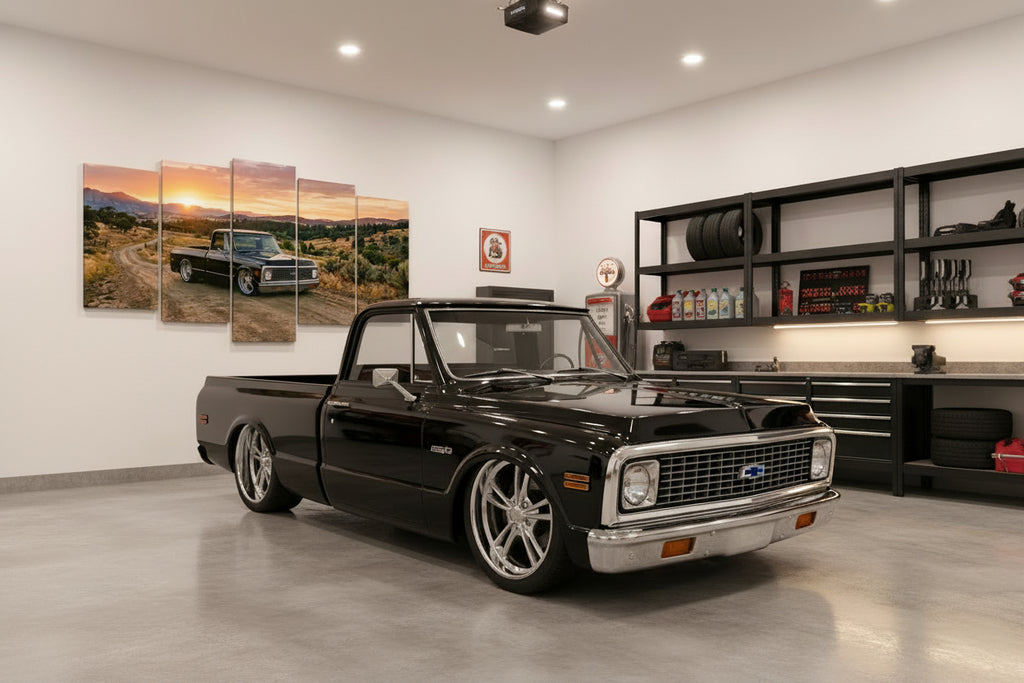 A five-panel canvas wall art print depicting a black vintage 1970 Chevy C10 Fleetside pickup truck driving on a dirt road at sunset, displayed above a green tufted sofa in a living room setting.