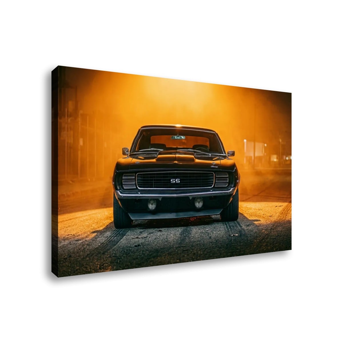 A rectangular wall art print or canvas showing a black 1969 RS/SS Chevy Camaro classic muscle car facing forward in a smoky, orange-lit street scene, photographed against a plain white background.