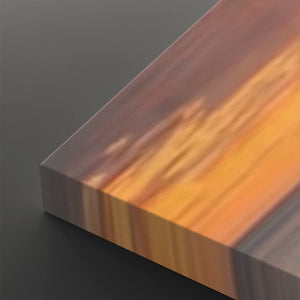 A close-up of a rectangular block or panel with a warm woodgrain-like pattern in orange, brown, and golden tones, shown against a dark gray background.