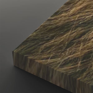 A close-up of a rectangular panel or board with a realistic grassy texture in brown, tan, and olive tones, shown at an angle against a dark gray background.