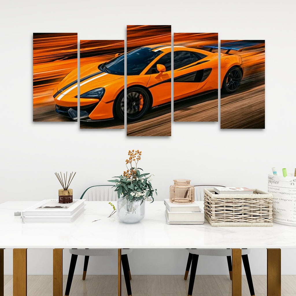 A five-panel canvas wall art set depicting a bright orange sports car in motion, displayed above a white dining table in a modern room setting.