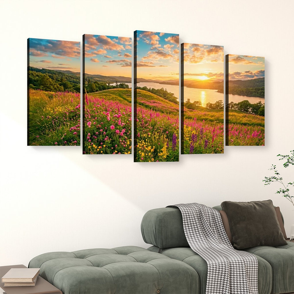 A five-panel canvas wall art set depicting a colorful sunset landscape with wildflowers, hills, and a lake, displayed above a green sofa in a living room setting.