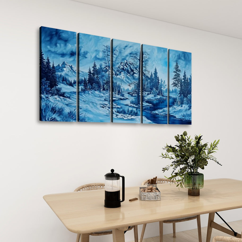 A five-panel canvas wall art set depicting a snowy mountain landscape in shades of blue, hung on a white wall above a light wood dining table with a coffee press and a potted plant.