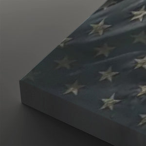A close-up of a rectangular panel or book-like object with a dark blue surface covered in raised white stars, photographed against a dark gray studio background.