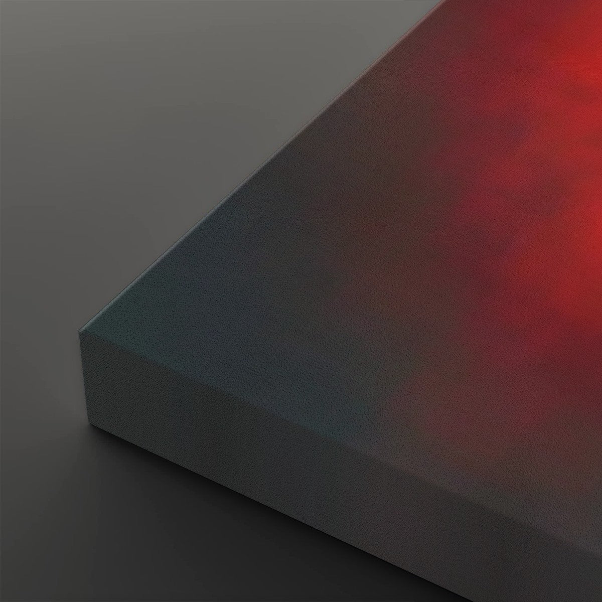 A close-up of a rectangular panel or block showing a smooth color gradient from dark gray to deep red, set against a dark gray background.