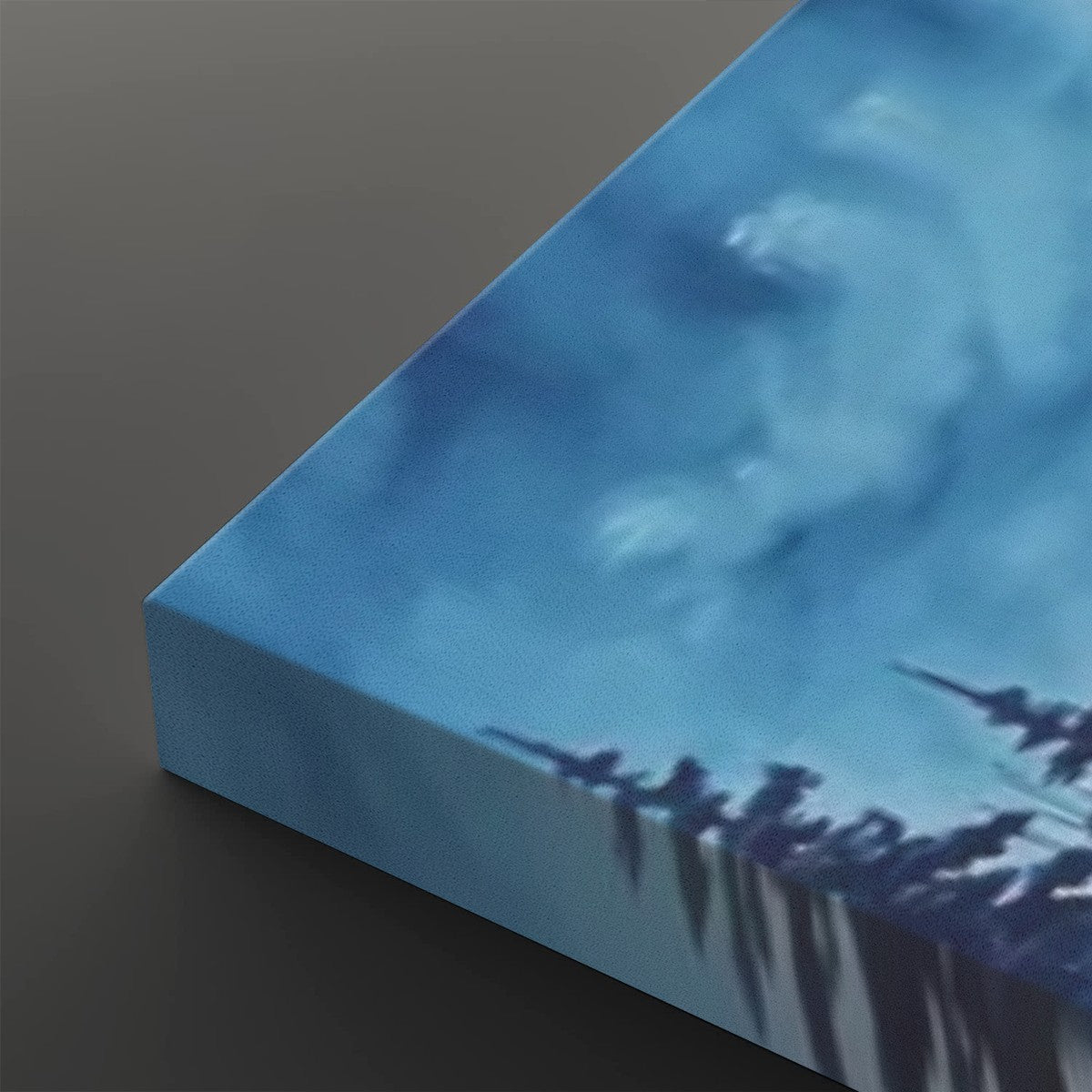 A close-up of a square canvas print showing its wrapped edge, featuring a blue-toned abstract landscape or sky scene with dark silhouetted shapes along the bottom, set against a dark gray background.