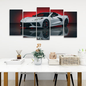 A multi-panel canvas wall art set depicting a white sports car with red accents, displayed above a white dining table in a modern room setting.