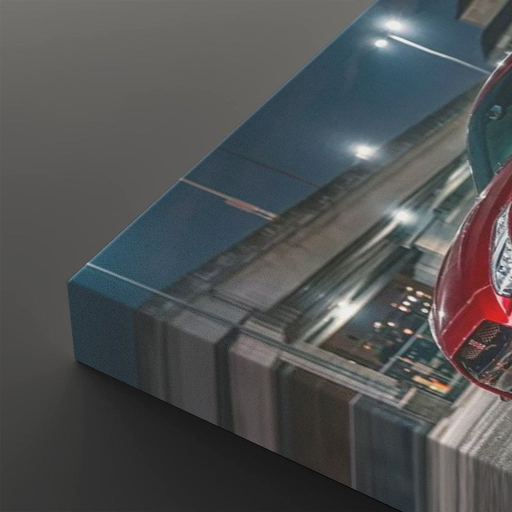 A rectangular canvas wall art print shown at an angle on a dark gray background. The artwork depicts a nighttime street scene with a red car and blurred motion lines, and the canvas itself has a blue side edge.