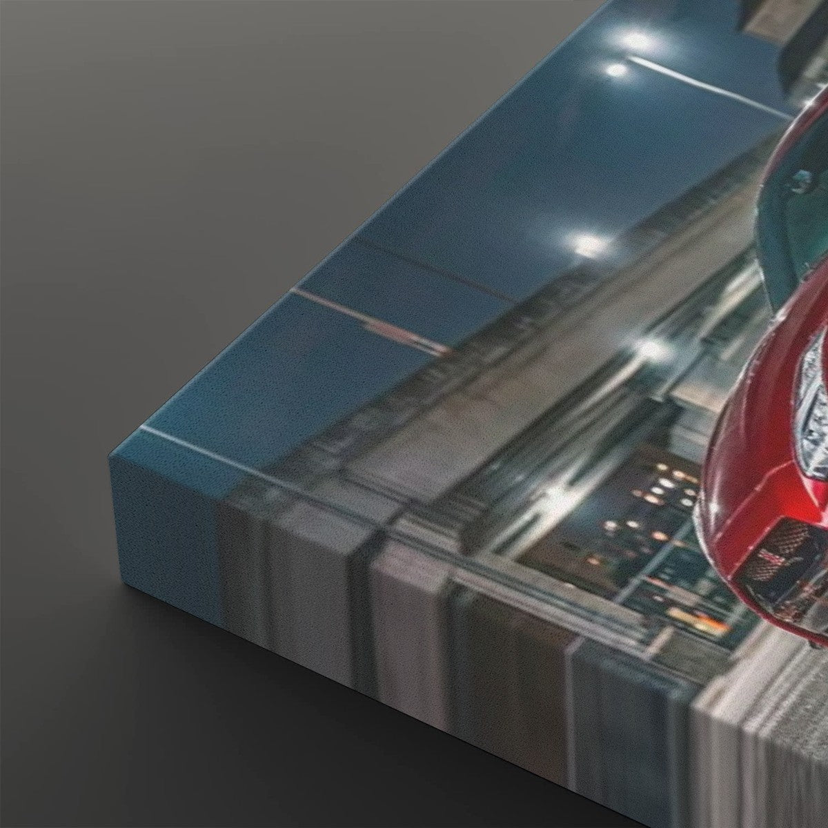 A rectangular canvas wall art print shown at an angle on a dark gray background. The artwork depicts a nighttime street scene with a red car and blurred motion lines, and the canvas itself has a blue side edge.