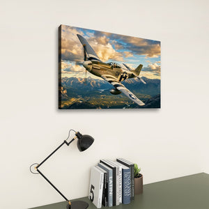 A rectangular wall art print showing a military fighter plane flying over mountains under a dramatic cloudy sky, displayed on a light wall above a desk with a lamp and books.