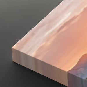A close-up of a rectangular canvas or panel with a soft abstract landscape print in peach, pink, cream, and muted blue tones, shown against a dark gray background.