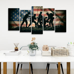 A five-panel canvas wall art set depicting the silhouette of five soldiers carrying a wounded comrade against a distressed American flag background, displayed on a white wall above a modern white dining table.
