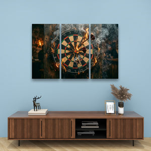 A three-panel canvas wall art set depicting a burning dartboard, displayed on a light blue wall above a wooden console table with decorative items.