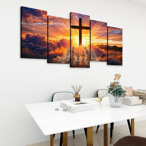 A 5-panel canvas wall art set depicting a dramatic sunset sky with a large cross and silhouetted figures, displayed above a white dining table in a modern room setting.