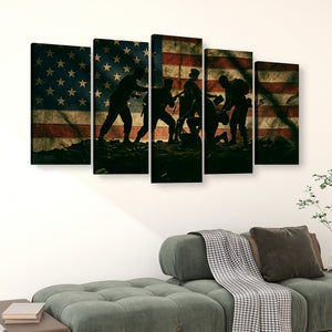 A five-panel canvas wall art set depicting the silhouette of soldiers carrying a wounded warrior against a distressed American flag background, displayed on a white wall above a green sofa.