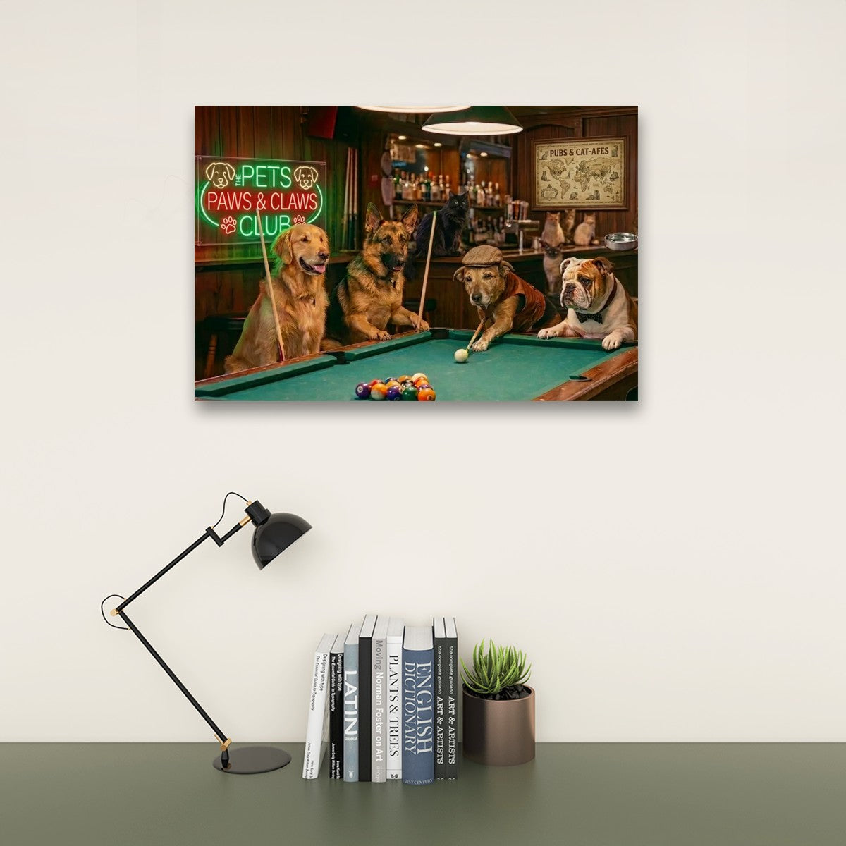 A rectangular wall art print showing three dogs playing pool in a bar scene, mounted on a light wall above a desk with a black lamp, books, and a small plant.