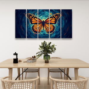 A four-panel canvas wall art set featuring a large orange and black butterfly over a swirling blue cosmic background, displayed above a light wood dining table with chairs and a vase in a modern room setting.