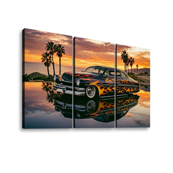 A three-panel canvas wall art print showing a black Mercury Sled with orange and yellow flames parked in reflective water at sunset, with palm trees and hills in the background.