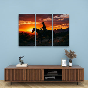A three-panel canvas wall art print depicting a cowboy riding a horse at sunset, displayed on a light blue wall above a wooden console table with decorative items.