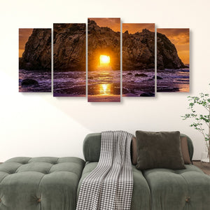 A five-panel canvas wall art set depicting a dramatic rocky coastline at sunset, displayed above a green sofa in a living room setting.