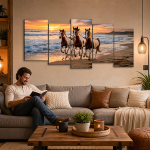 A 4-panel canvas wall art set depicting three galloping horses on a beach at sunset, displayed on a beige wall above a gray sofa in a cozy living room setting.