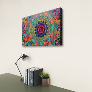 A colorful abstract mandala canvas wall art print hanging on a light beige wall above a dark green desk with a black desk lamp, books, and a small potted succulent.