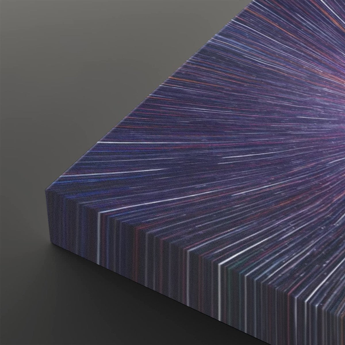A close-up of a rectangular panel or book-like object with a radiating striped pattern in deep purple, blue, pink, and white, shown against a dark gray background.