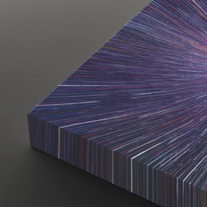 A close-up of a rectangular panel or book-like object with a radiating striped pattern in deep purple, blue, pink, and white, shown against a dark gray background.