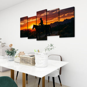 A 4-panel canvas wall art set depicting a cowboy riding a horse through a sunset landscape, displayed on a white wall above a dining table in a modern room setting.