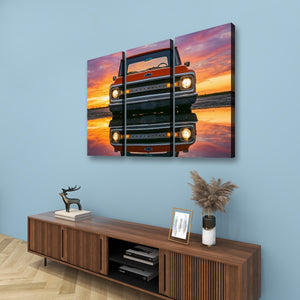 A three-panel canvas wall art print depicting a red vintage  1970 Chevrolet C10 truck truck reflected in water at sunset, displayed on a light blue wall above a wooden console table with decorative items.
