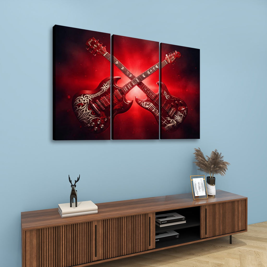 A three-panel canvas wall art set depicting two crossed red electric guitars with tribal-style patterns, displayed on a light blue wall above a wooden console table with decorative items.
