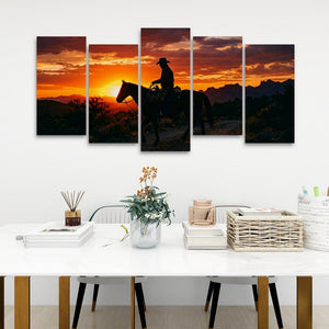 A five-panel canvas wall art set depicting a cowboy riding a horse at sunset, displayed on a white wall above a styled dining table with books, a vase, and baskets.