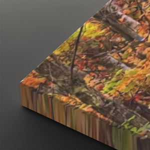 A close-up angled view of a rectangular canvas or print showing an autumn forest scene with yellow, orange, brown, and green leaves, photographed against a dark gray background.
