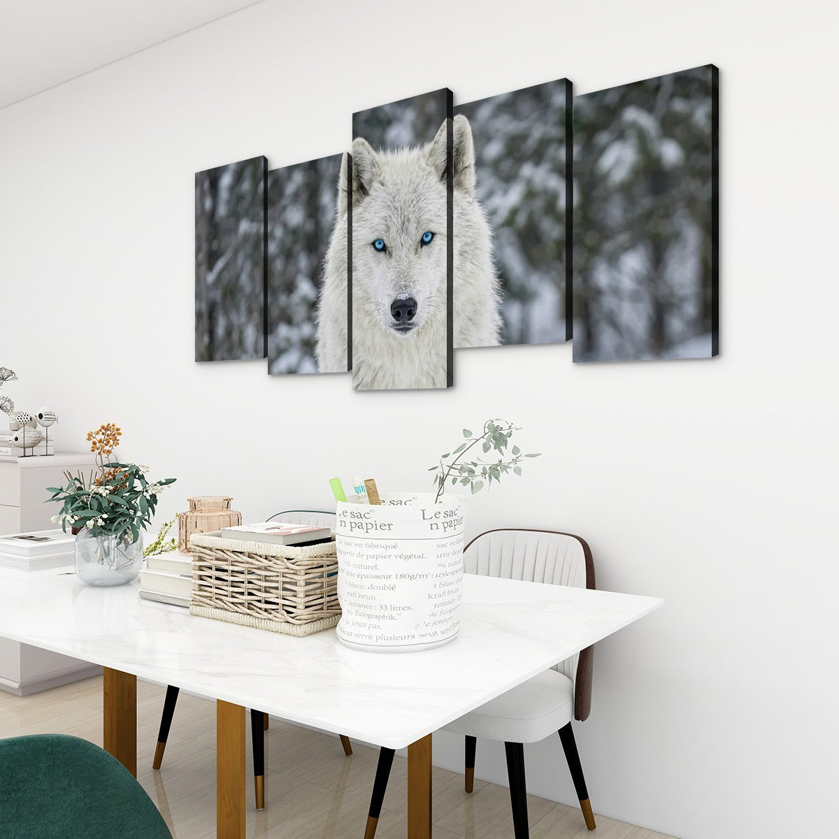 A five-panel canvas wall art set depicting a close-up of a white wolf with bright blue eyes in a snowy forest, displayed on a white wall above a dining table in a modern room setting.