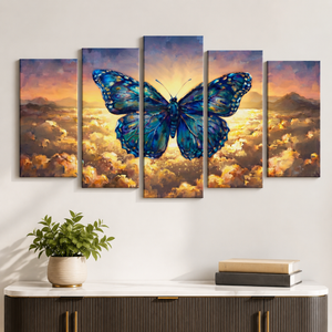 A 5-panel canvas wall art set depicting a large blue butterfly over a glowing sunset sky and clouds, displayed above a console table with a potted plant and books in a styled room setting.