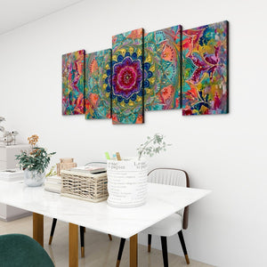 A five-panel canvas wall art set featuring a vibrant, colorful mandala and abstract floral design, displayed on a white wall above a dining table in a modern room setting.