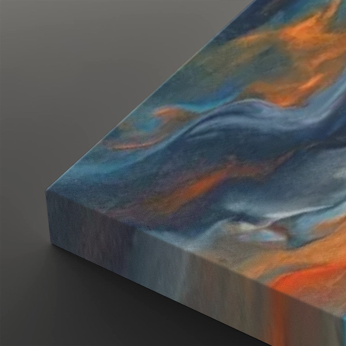 Abstract canvas wall art showing a marbled swirl pattern in shades of blue, gray, white, and orange, photographed at an angle on a dark gray background.