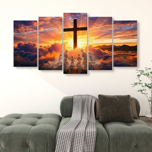 A 5-panel canvas wall art set depicting a dramatic sunset sky with a large cross, clouds, and silhouetted figures, displayed above a green sofa in a living room setting.