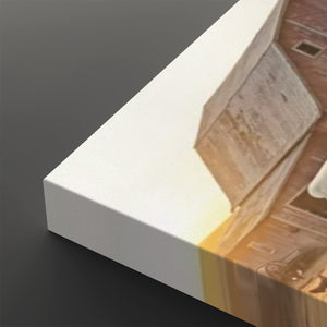 A close-up of a canvas print showing its white wrapped edge and printed artwork of a warm-toned architectural scene, set against a dark gray background.