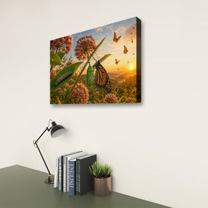 A rectangular wall art print showing a butterfly and flowers at sunset, displayed on a white wall above a desk with books, a lamp, and a small plant.