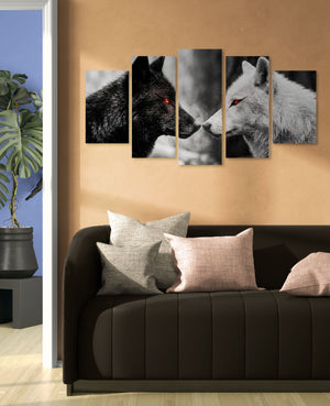 Five-panel wall art of wolves on a beige wall above a black sofa with gray and beige cushions.